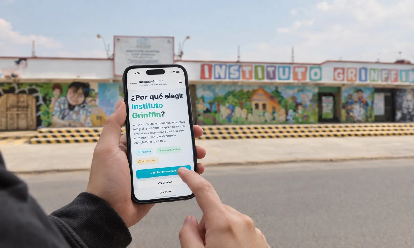 Una mano sostiene un celular con el sitio del Instituto Grinffin abierto, frente a la fachada de la escuela.